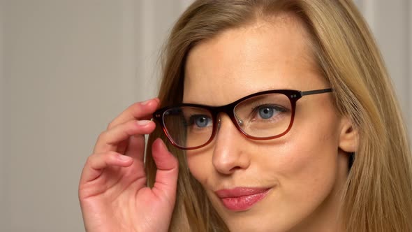 Female Model Facing Sideways Holds her Glasses and LetsHand Slide Down