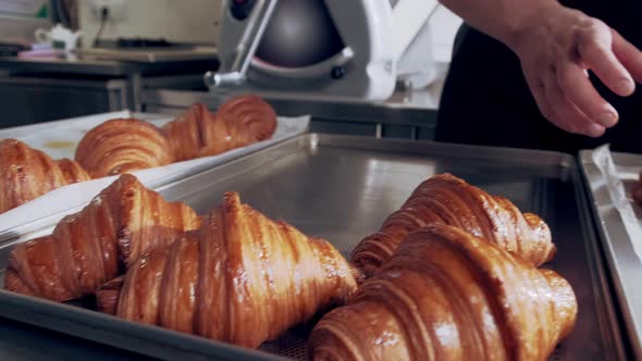 Baker Places Freshly Baked French Croissants on Baking Sheet
