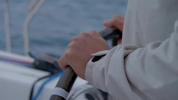 Hands of the skipper at the helm control of sailing boat