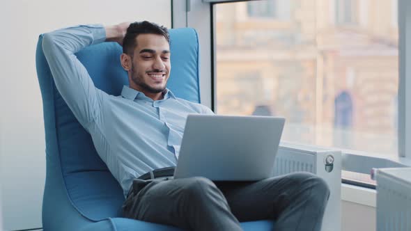 Relaxed Happy Indian Businessman Student Worker Sits in Comfortable Armchair Meditating Positive