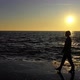 Slow motion female walking by the ocean with waves on sunset - VideoHive Item for Sale