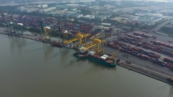 Drone flying in over Saigon river and port in Ho Chi Minh City, Vietnam with container ship and larg