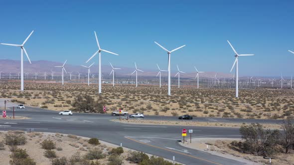 Renewable onshore turbines in wind farm generating green energy by countryside expressway and traffi