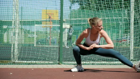 Young Fit Sporty Pretty Female in Sportswear Stretching Legs at Sports Ground