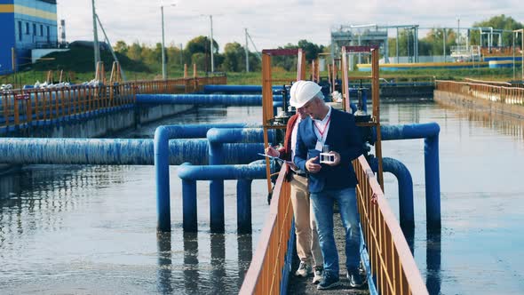 Two Engineers Are Passing By the Outdoors Wastewater Facilities. Wastewater Treatment Concept.