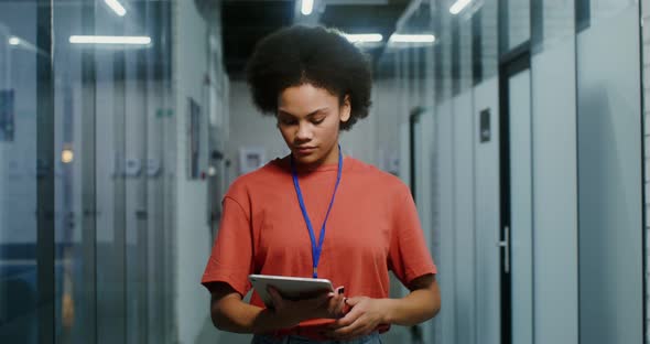 A AfricanAmerican Woman Uses a Digital Tablet Then Looks at Camera with Smile