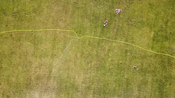 Top down aerial view of football field surface covered with green grass and sprinklers spraying 