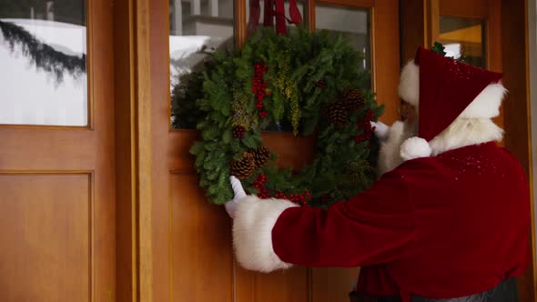 Santa Claus putting wreath on door