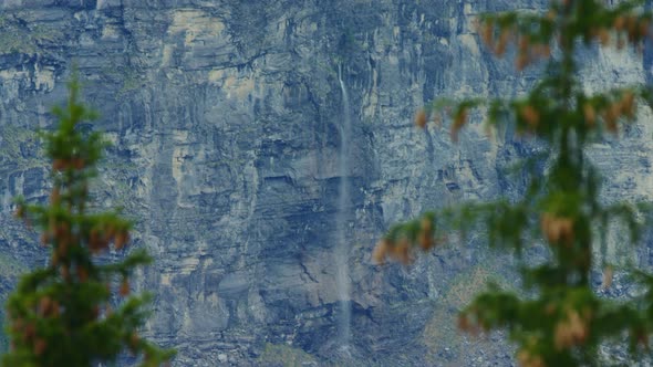 A huge waterfall flows out from the middle of a cliff