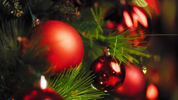 Red Christmas Ball on a Christmas Tree with a Garland on the Background of a Wooden Wall 