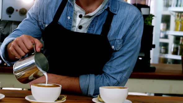 Smiling waiter making cup of coffee at counter