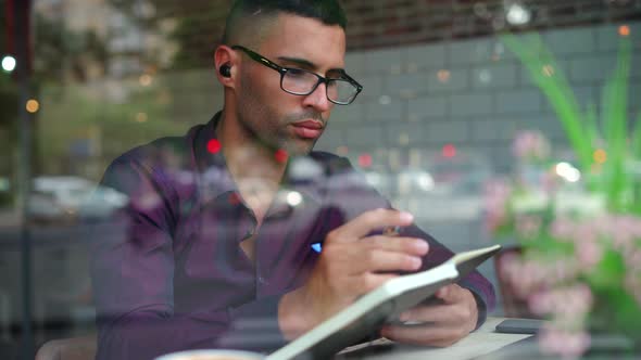 Hispanic male entrepreneur reading notes in cafe