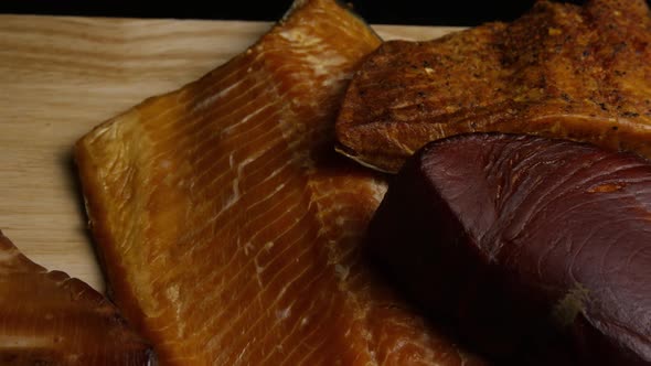 Rotating shot of a variety of delicious, premium smoked meats on a wooden cutting board 