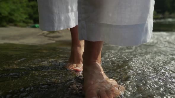 Feet walking in current of very shallow section of river.