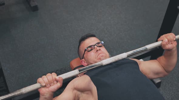 An Arab Man Shakes His Chest with a Barbell Lying Down