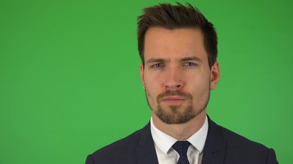 A Young Handsome Businessman Looks Seriously at the Camera - Closeup - Green Screen Studio