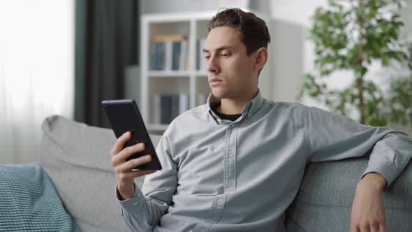 Relaxed Man Sitting on Sofa with Tablet