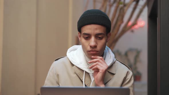 Pensive Arabian man working on laptop