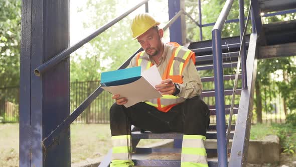 Architect Sitting On Stairs Looking Blueprint Analyzing Building Structure Problems