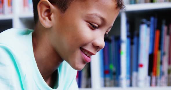 Portrait of schoolboy smiling in library at school