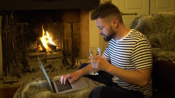 Man is Working on a Laptop Near the Fireplace