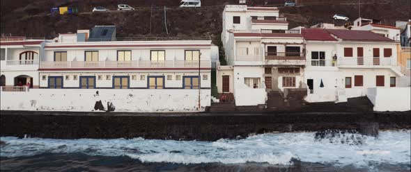 Aerial view of a man seated on the stairs of a house at a coastal village