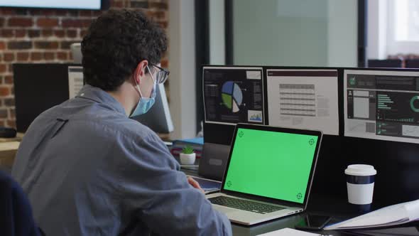 Man wearing face mask using laptop at office