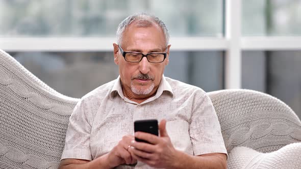 Focused 70s Elderly Man Hold Mobile Surfing Internet