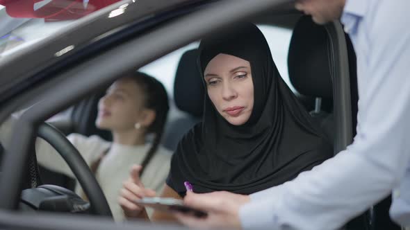 Confident Gorgeous Woman in Hijab Signing Purchase and Sale Agreement Sitting on Driver's Seat in