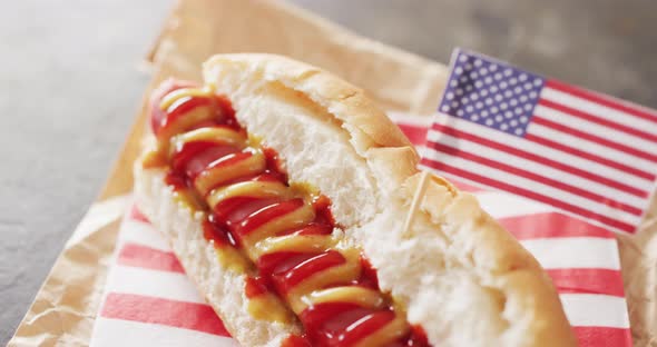 Video of hot dog with mustard and ketchup with flag of usa on a black surface