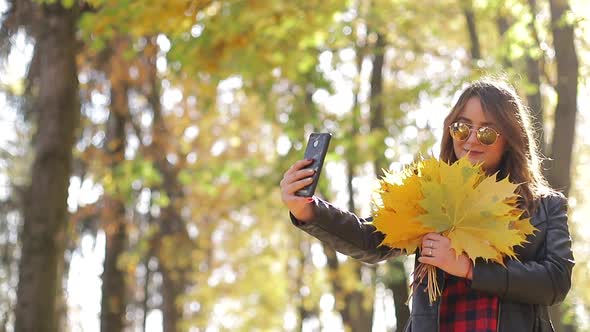Beautiful teenage girl taking Selfie on smartphone outdoors in Park on Sunny autumn day