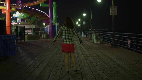 Young woman walking by the Pacific Park, at night