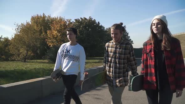 Teenagers with Skateboards Walk Outdoors