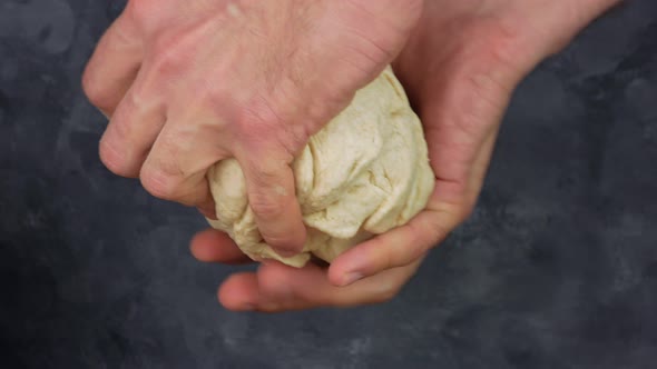 Male hands kneading pizza dough, man making bread with wholegrain wheat flour and semolina