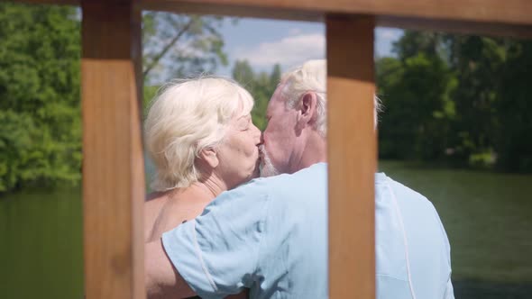 Happy Mature Couple Sitting on the Bench Near the River, Admiring Nature