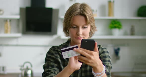 Young Woman Is Entering Credit Card Number, Looking at Gadget Sceen