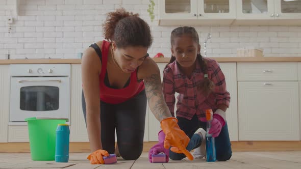 Mom and Girl Wiping Floor with Cleaning Supplies