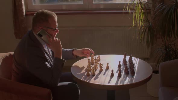 Businessman Makes an Important Decision By Talking on Phone and Playing Chess