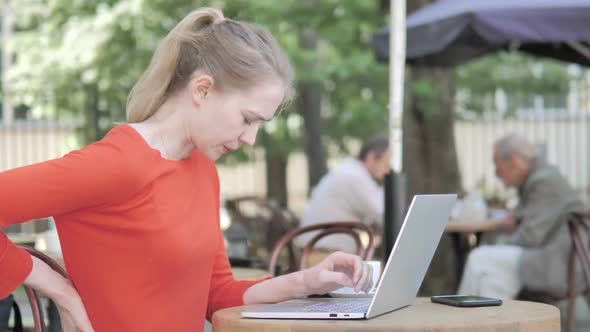 Young Woman Working on Laptop and Drinking Coffee Sitting in Cafe Terrace