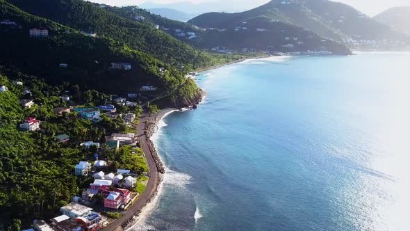 Aerial British Virgin Island Tortola beach fly by of local homes on the water angle 1
