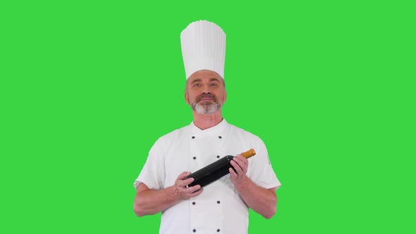 Senior Chef Holding a Bottle of Perfect Red Wine and Smiling To Camera on a Green Screen Chroma Key