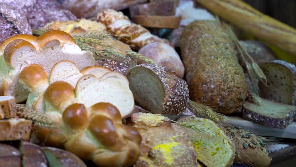 Lots of mixed bread and buns on the table in the bakery. Close-ups  braided bread.