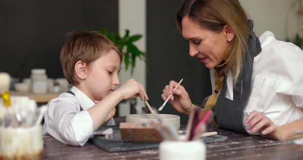 Mom and Her Son Draw a Clay Bowl Together in a Pottery Studio Workshop