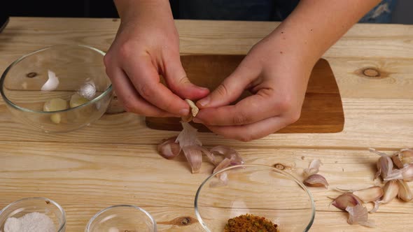 Peeling garlic from husks in the home kitchen. A woman's hands peel garlic and put it in a bowl