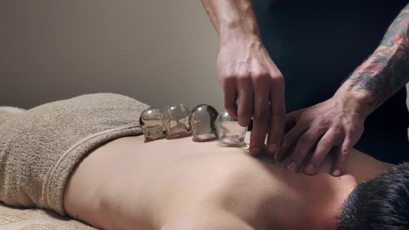 Cupping massage. Young man enjoying back and shouders massage in spa