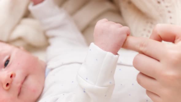 Closeup of Newborn Baby Boy Holding and Catching Mother's Finger with Little Hands