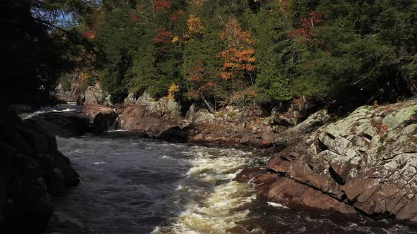 rapids in fall colored forest reveal small waterfalls