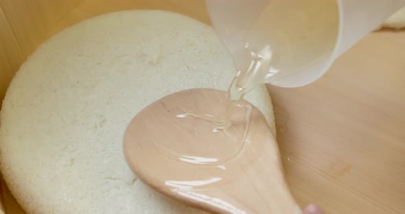 Sushi Rice Preparation- Pouring Vinegar On The Rice With A Wooden Spoon - POV - overhead shot, rotat