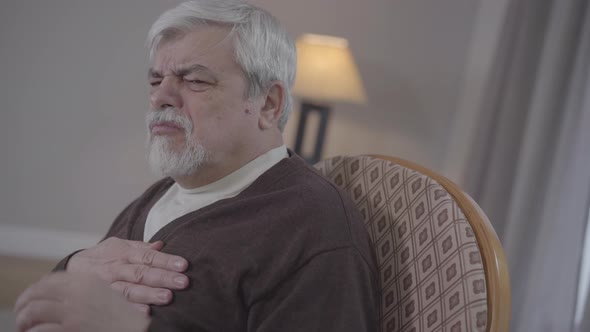 Side View of Old Caucasian Man Having Sudden Sharp Pain in Chest and Calling Emergency. Portrait of