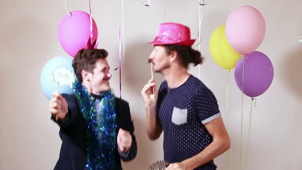 Two happy men dancing with props in photo booth